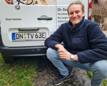 Nicolas Kallscheuer kniet vor der Rückseite des Wagens neben dem Nummernschilds DN-TV 63E