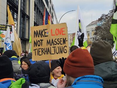 Eine Gruppe Menschen mit einem Plakat "Make love, not Massentierhaltung".