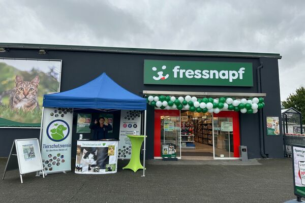 Ein überdachter Infostand mit Theke und Roll-ups, neben einem mit Luftballons geschmückten Fressnapf-Eingang.