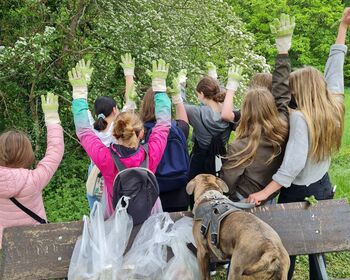 Mitglieder der Jugendgruppe strecken im Wald  ihre behandschuhten Hände in die Höhe.