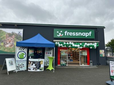 Ein überdachter Infostand mit Theke und Roll-ups, neben einem mit Luftballons geschmückten Fressnapf-Eingang.