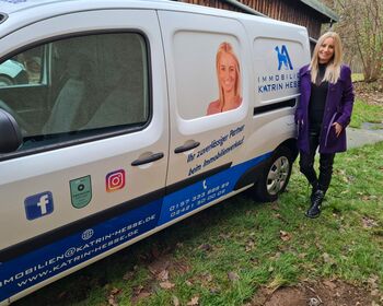 Immobilienmaklerin Katrin Hesse neben dem Fahrzeug mit Werbeaufdruck ihres Unternehmens.