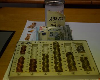 Geldzählbrett mit Münzen, Geldscheine und Spendendose. Auf einem Zettel steht der Spendenerlös und die 50 € der Familie Stein geschrieben. geschrieben