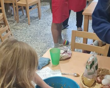An Tischen im Gruppenraum bereiten die Kinder die Speisen zu.